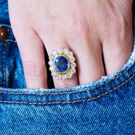 Vintage 1960s French sapphire and diamond cluster ring worn on hand resting in denim pocket.