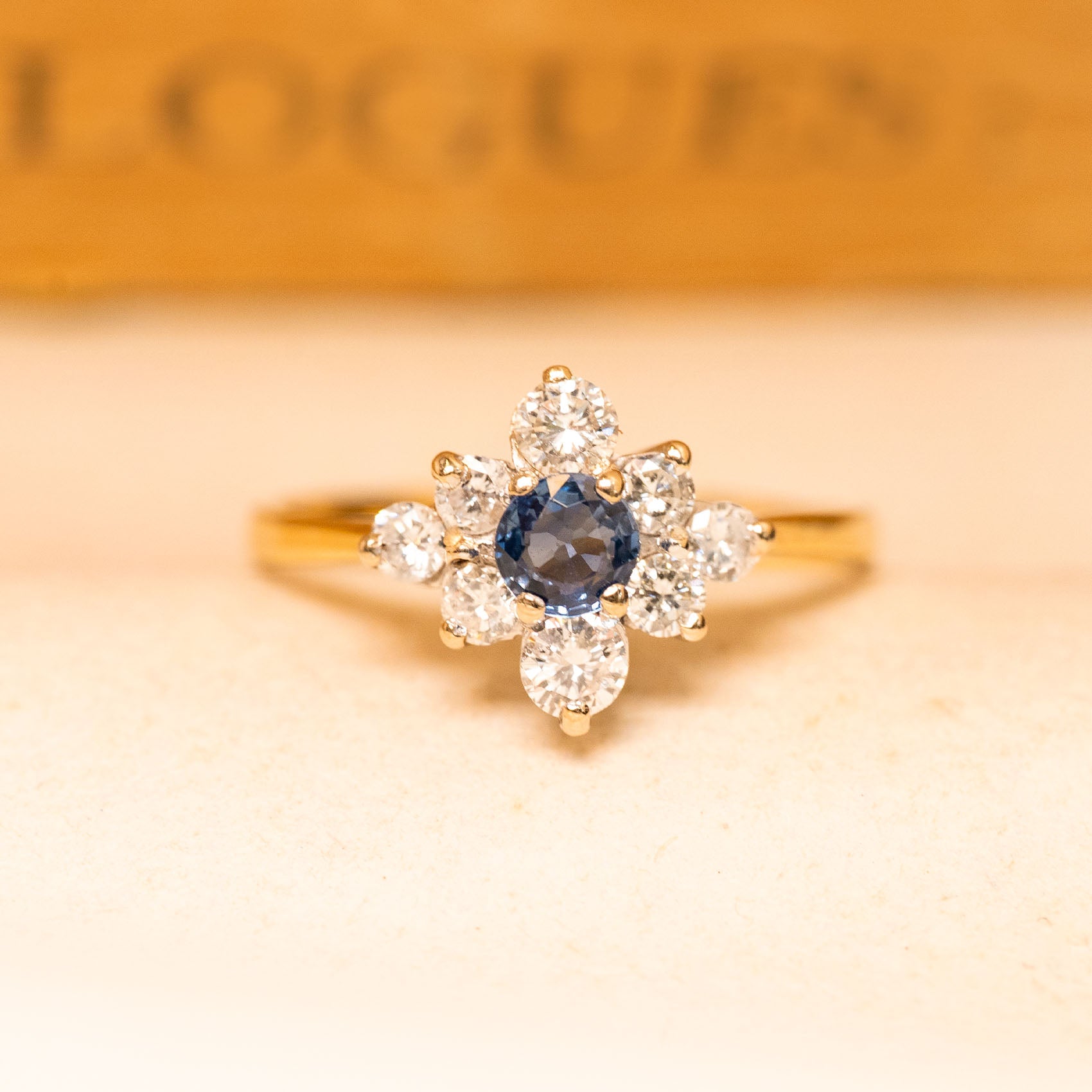 Vintage 1990s sapphire and diamond cluster ring featuring a deep blue sapphire surrounded by brilliant-cut diamonds in yellow gold.