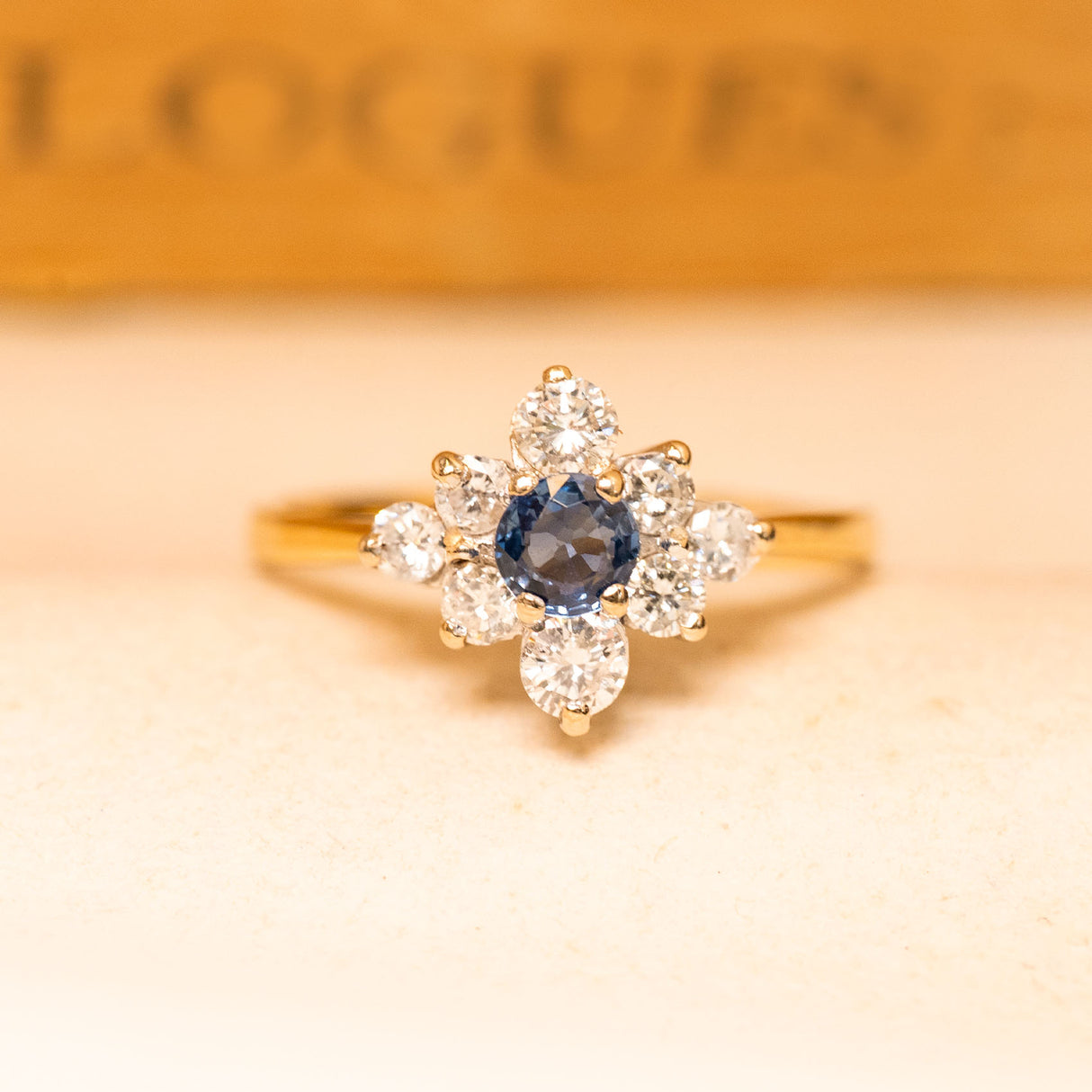 Vintage 1990s sapphire and diamond cluster ring featuring a deep blue sapphire surrounded by brilliant-cut diamonds in yellow gold.