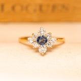 Vintage 1990s sapphire and diamond cluster ring featuring a deep blue sapphire surrounded by brilliant-cut diamonds in yellow gold.