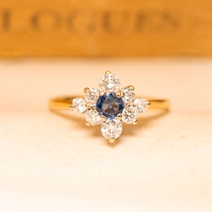 Vintage 1990s sapphire and diamond cluster ring featuring a deep blue sapphire surrounded by brilliant-cut diamonds in yellow gold.