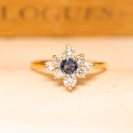 Vintage 1990s sapphire and diamond cluster ring featuring a deep blue sapphire surrounded by brilliant-cut diamonds in yellow gold.
