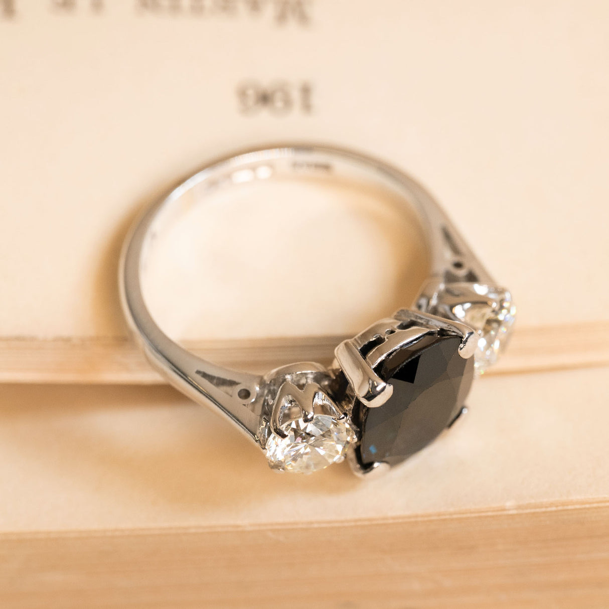 Vintage 1970s sapphire and diamond three-stone ring with a rich midnight-blue oval sapphire accented by round brilliant-cut diamonds in white gold.