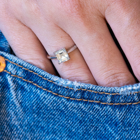 Vintage solitaire diamond ring styled with denim pocket.