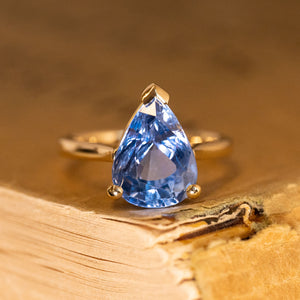 Pear-cut blue sapphire solitaire engagement ring featuring a vibrant blue sapphire in a classic three-claw yellow gold setting.