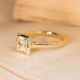 Princess-cut diamond solitaire ring with a brilliant square-cut diamond and refined yellow gold band.