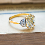 Vintage yellow oval diamond ring with symmetrical half-moon diamond side stones and gold band.