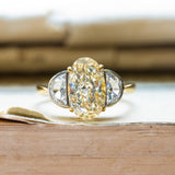 Vintage yellow oval diamond and half-moon diamond three-stone ring with elongated centre diamond and tapered side stones.