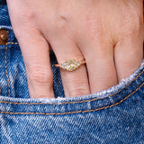 Antique-inspired primrose yellow diamond cluster tre-foil engagement ring worn on hand with denim pocket styling.