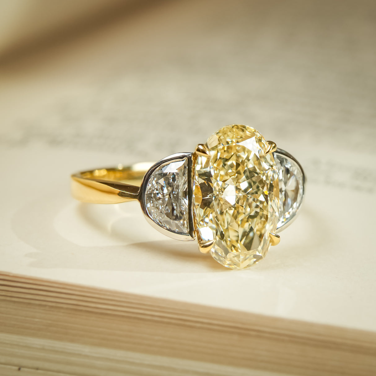 Yellow diamond oval three stone ring featuring half moon diamonds
