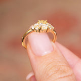 Antique-inspired primrose yellow diamond cluster tre-foil engagement ring showing raised gallery setting and gold band.