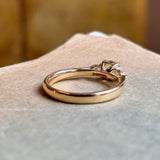 Rear view of yellow gold engagement ring with round green sapphire and diamond side stones.