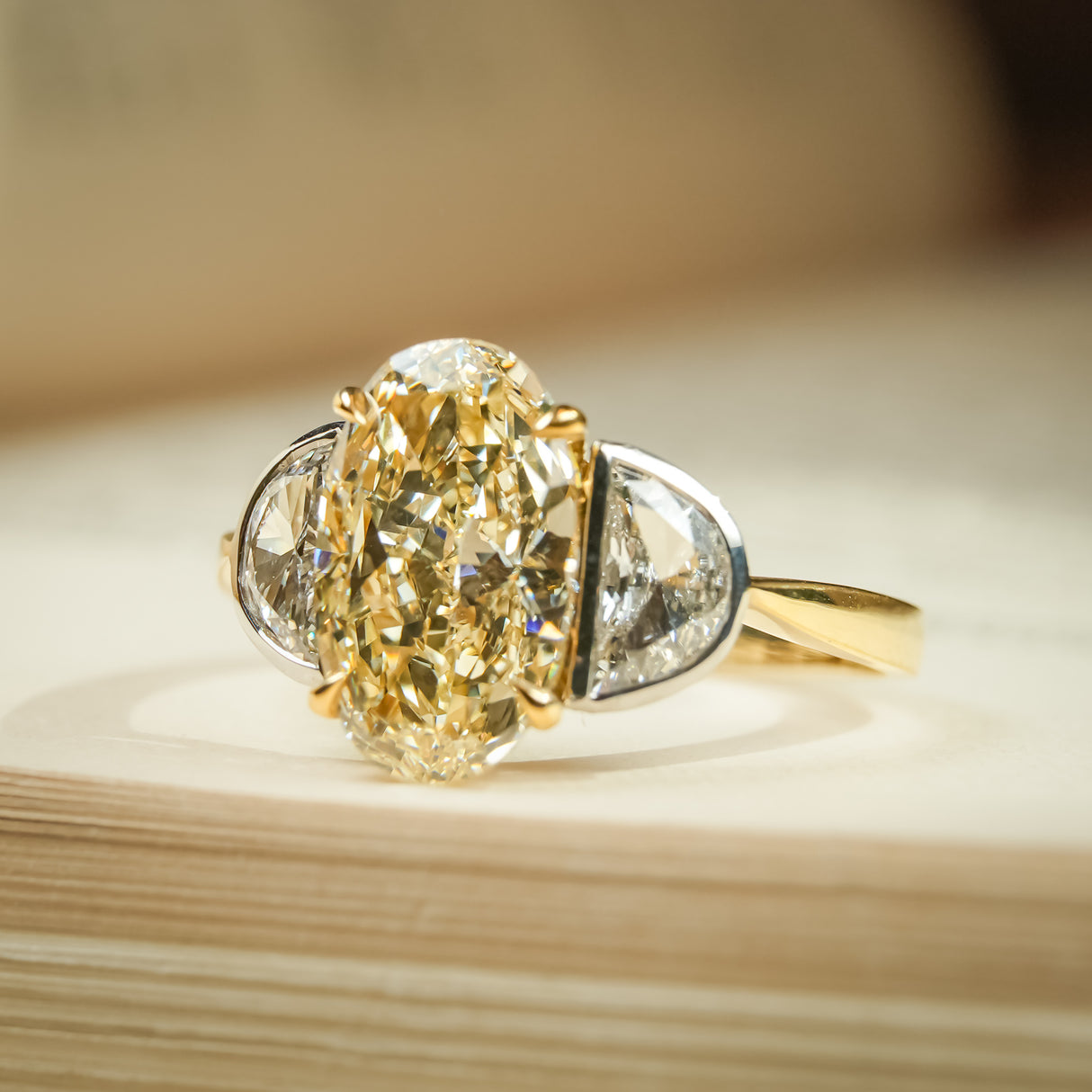 Yellow oval diamond engagement ring featuring half moon diamond side stones