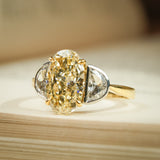 Yellow oval diamond engagement ring featuring half moon diamond side stones