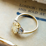 Vintage yellow oval diamond three-stone ring with half-moon side diamonds and polished gold band.
