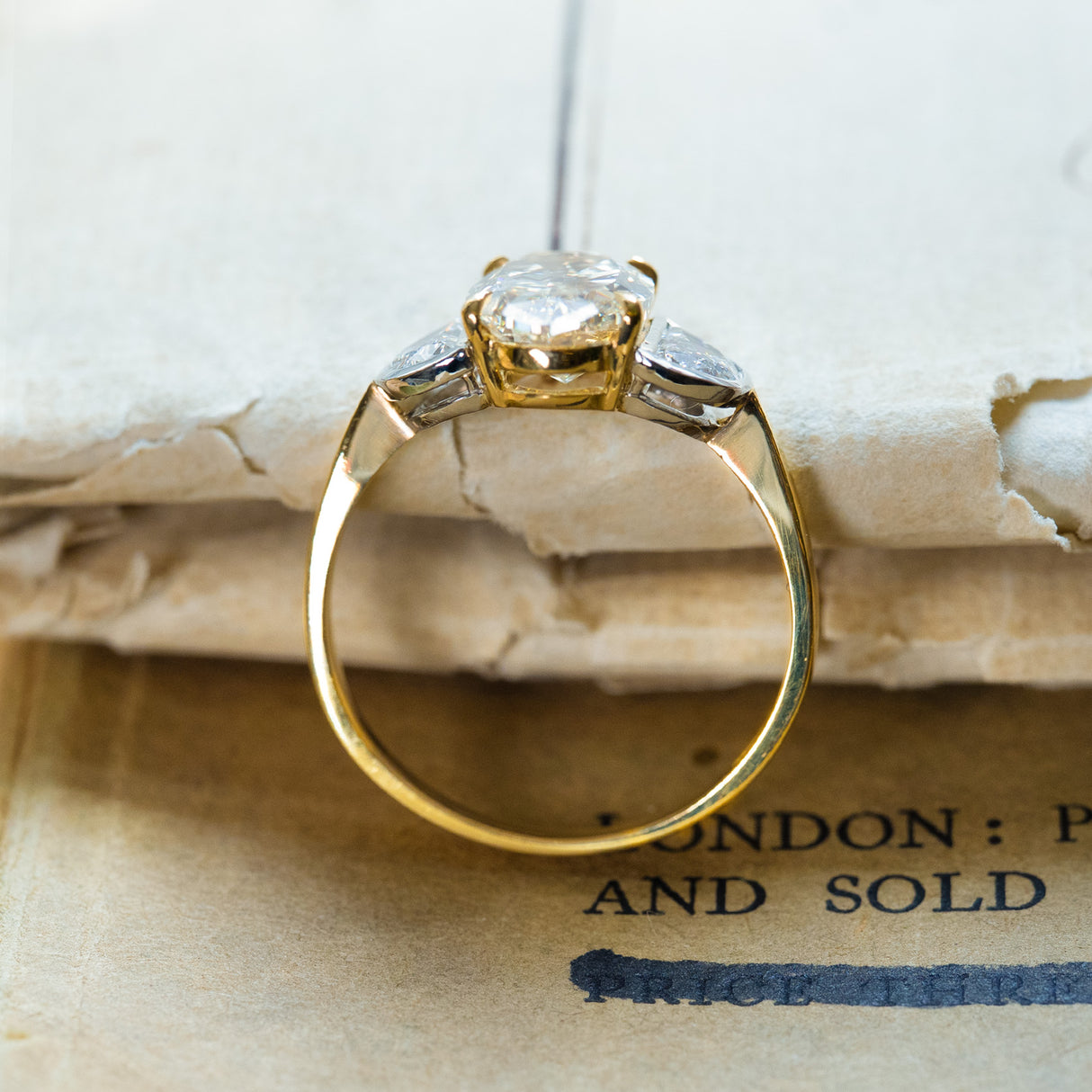 Vintage yellow oval diamond and half-moon diamond three-stone ring with open gallery beneath centre stone.