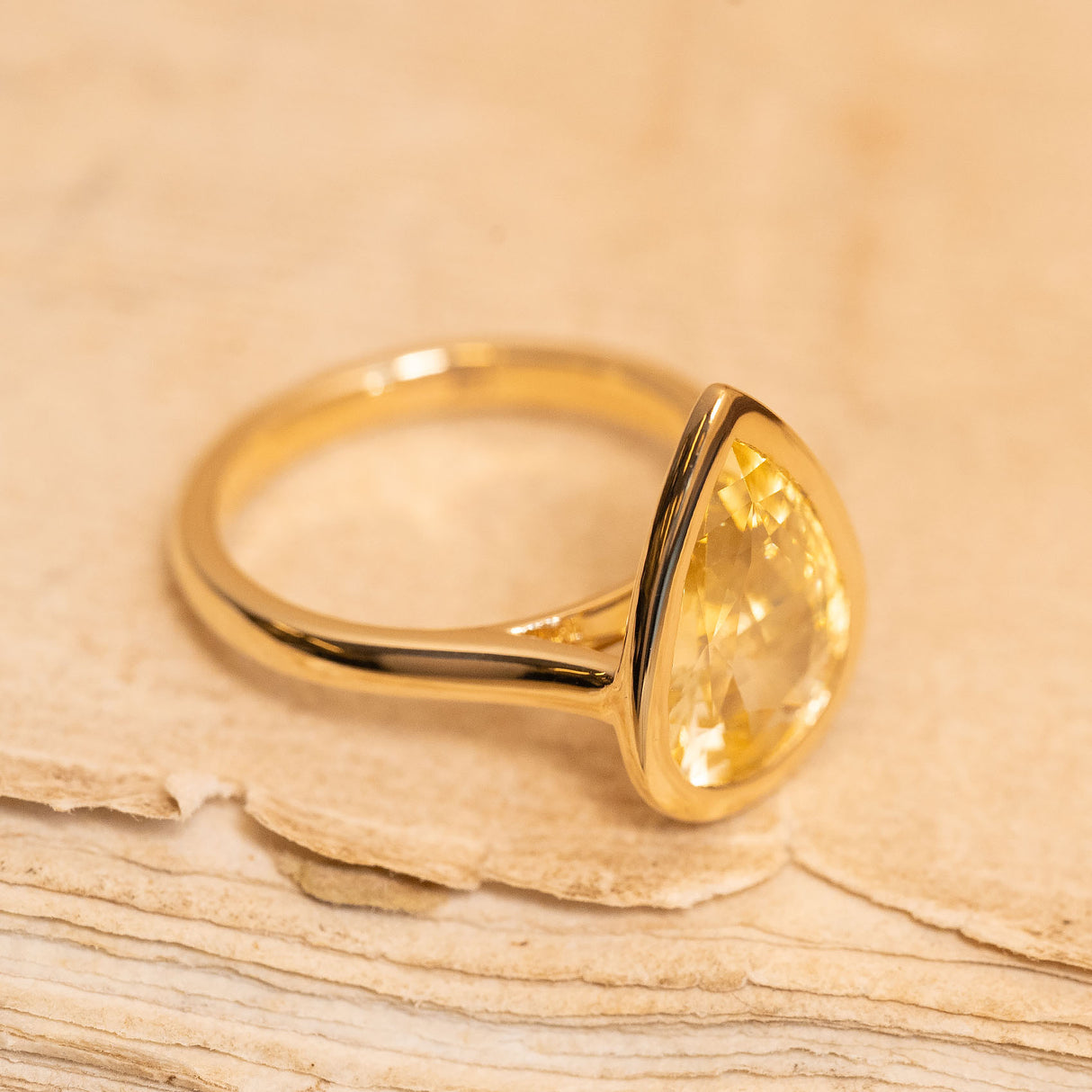 Pear-cut canary yellow sapphire solitaire ring with a bright yellow gemstone and elegant yellow gold band.