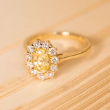 Oval-cut yellow sapphire engagement ring with a warm golden centre stone encircled by bright diamonds in an elegant antique-inspired setting.