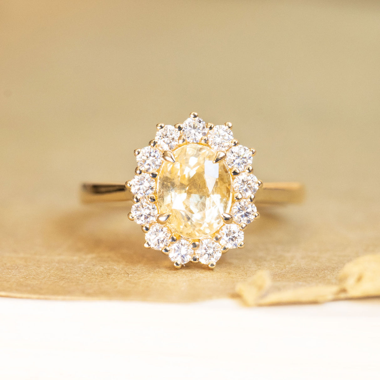 Yellow sapphire and diamond cluster engagement ring with oval-cut yellow sapphire in yellow gold.