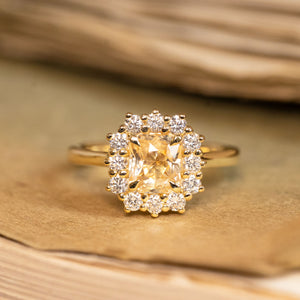Yellow sapphire and diamond cluster engagement ring featuring a radiant yellow sapphire surrounded by brilliant-cut diamonds in yellow gold.