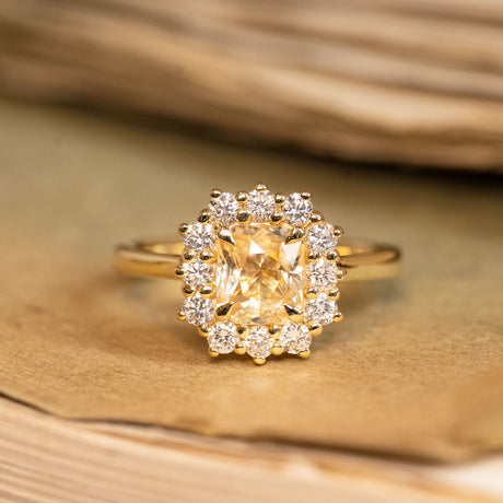 Yellow sapphire and diamond cluster engagement ring featuring a radiant yellow sapphire surrounded by brilliant-cut diamonds in yellow gold.