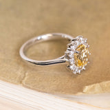 Antique-inspired yellow sapphire and diamond cluster engagement ring showcasing an emerald-cut yellow sapphire framed by a sparkling diamond cluster.