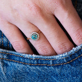 Close-up of a hand wearing an antique zircon ring with a denim pocket detail.