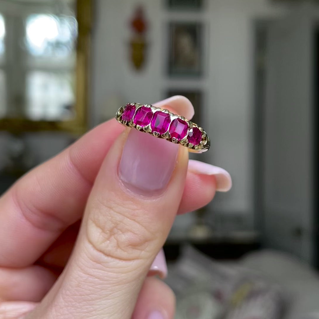 Edwardian five stone ruby band, held in fingers and moved around to give perspective.