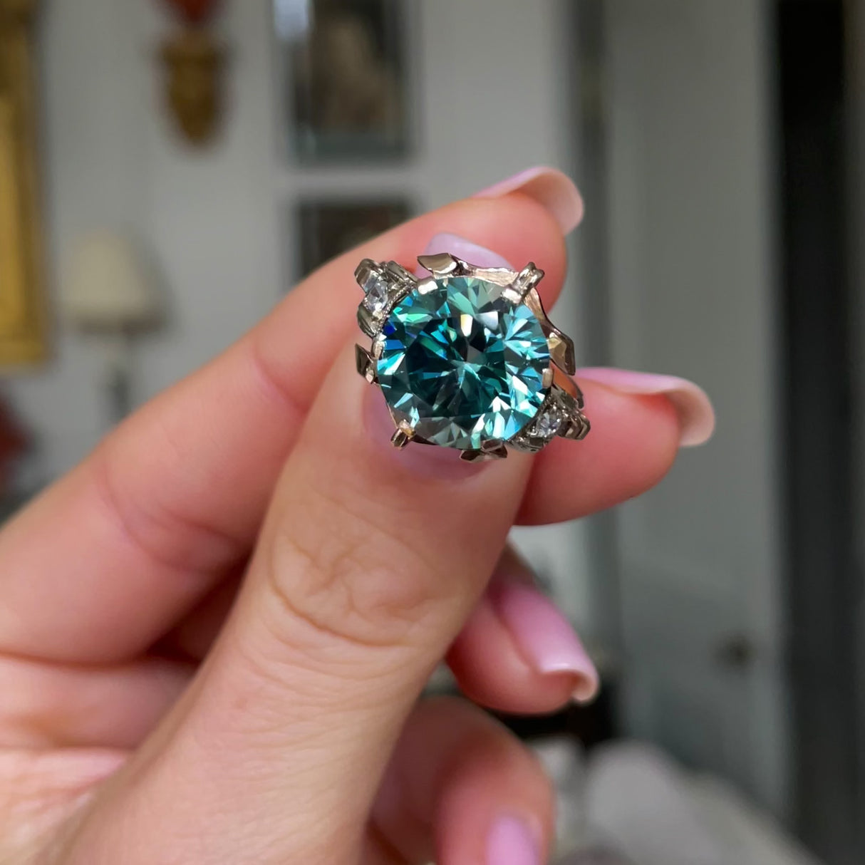 Art Deco zircon and diamond engagement ring, held in fingers and moved around to give perspective.