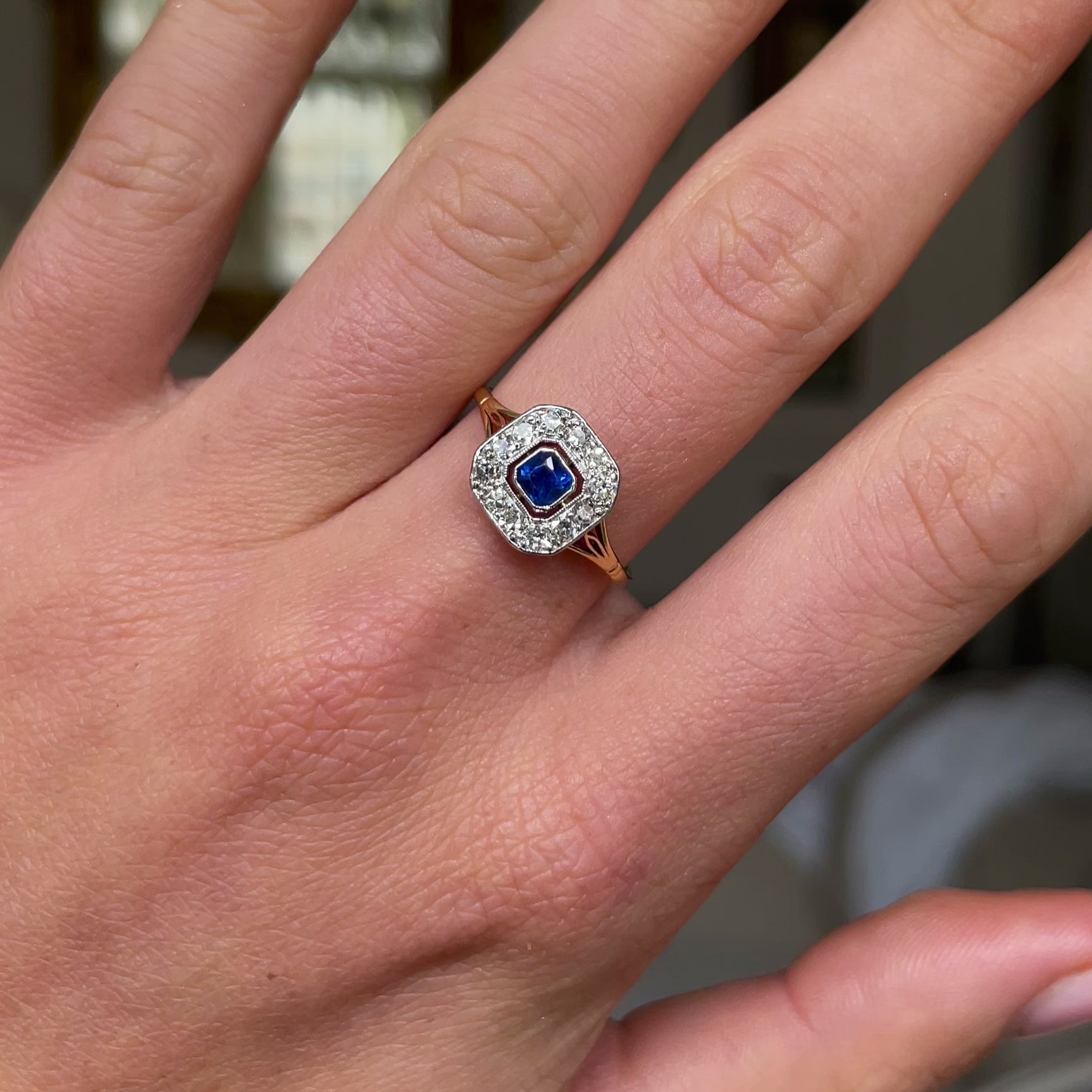 Sapphire and diamond engagement ring, worn on hand and rotated to give perspective.