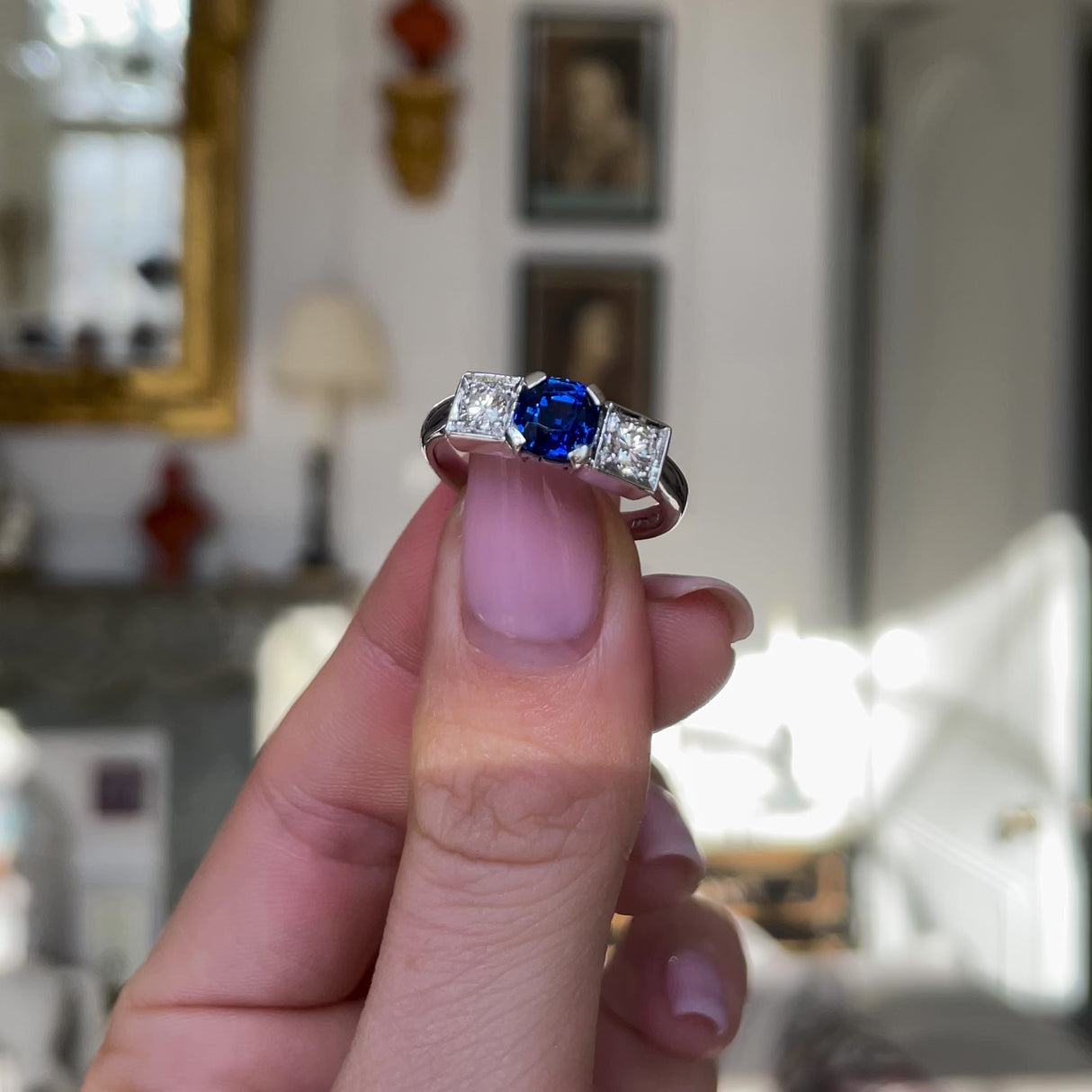 Art Deco three stone sapphire and diamond ring, held in hands and rotated to give perspective.