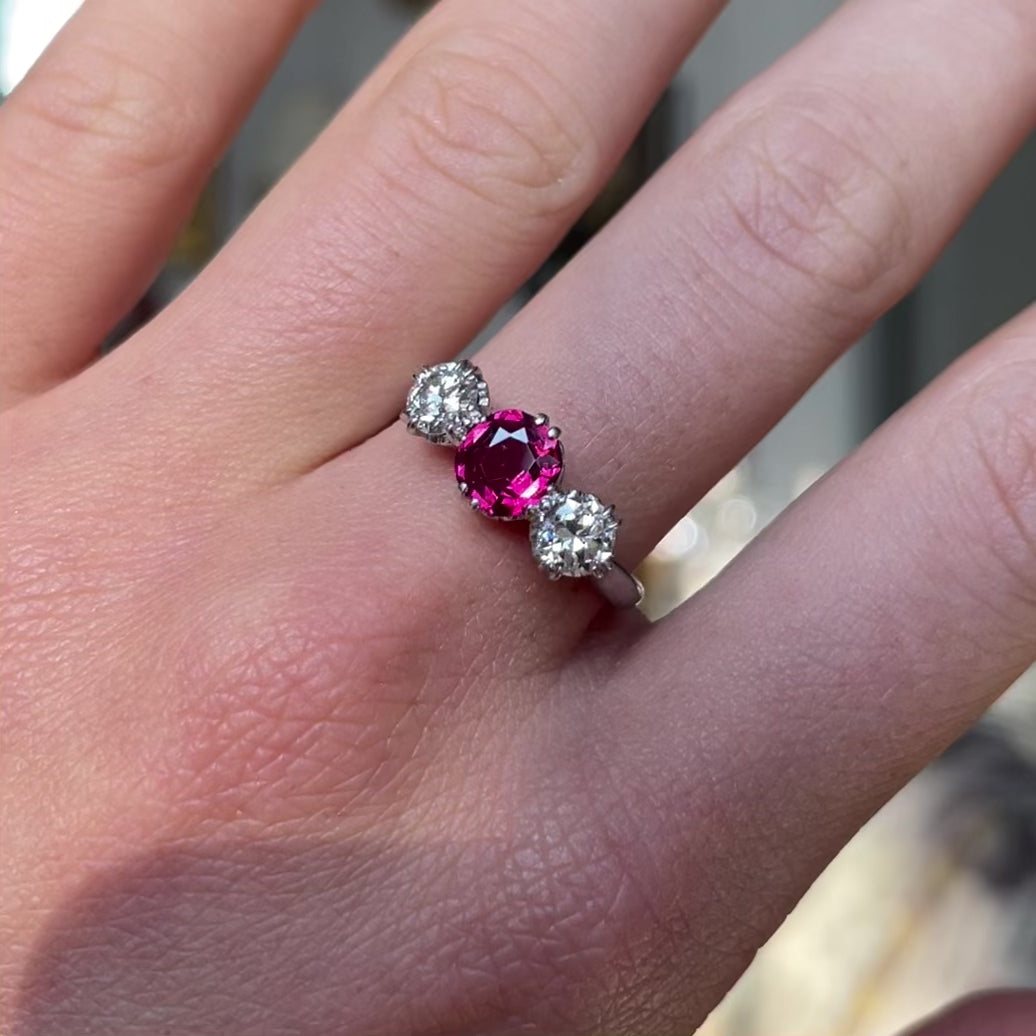 Ruby and diamond three-stone engagement ring, worn on hand and moved around to give perspective.