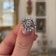 Antique French diamond cluster engagement ring, held in fingers and rotated to give perspective.