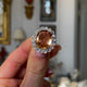 Edwardian, topaz and diamond cluster cocktail ring, held in fingers and rotated to give perspective.