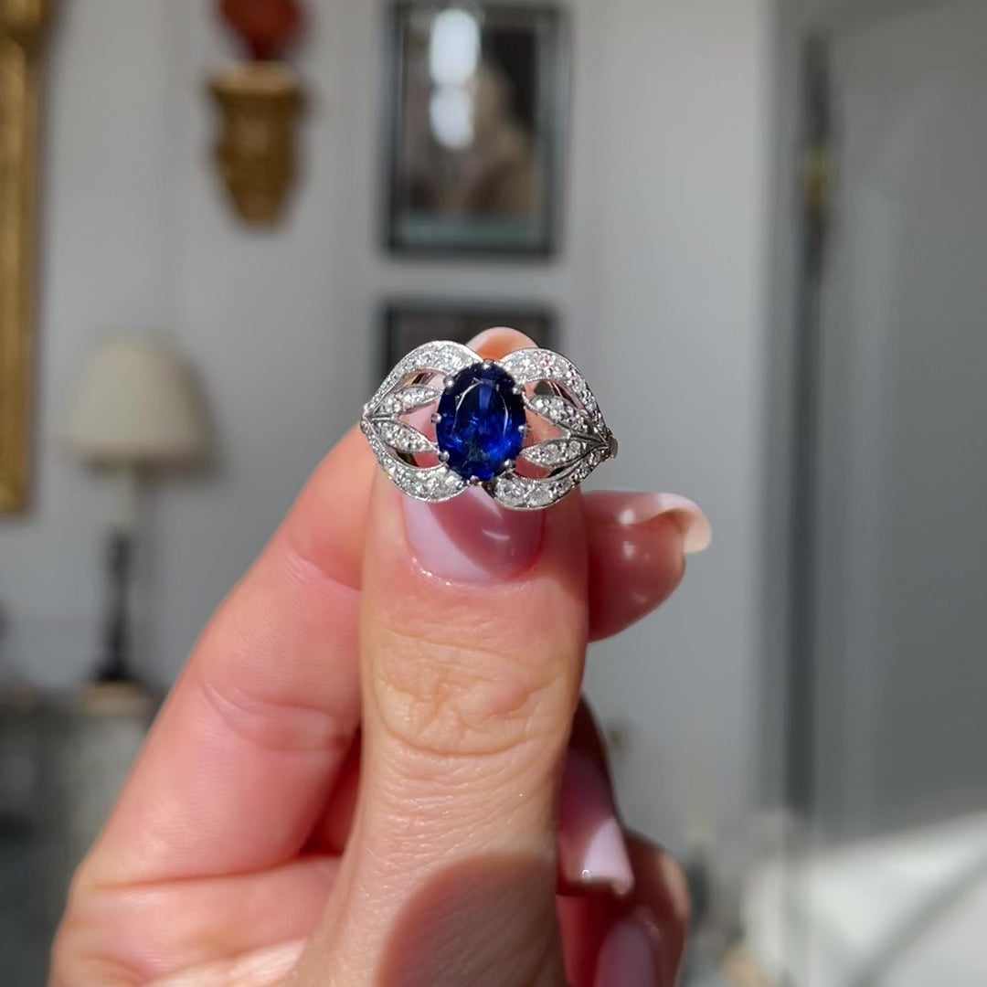 Art Nouveau, sapphire and diamond ring, held in fingers and rotated to give perspective.