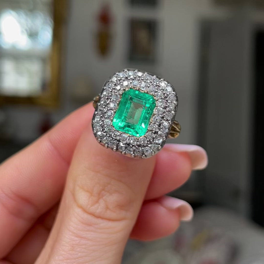 Georgian emerald and diamond cluster, held in fingers and rotated to give perspective.