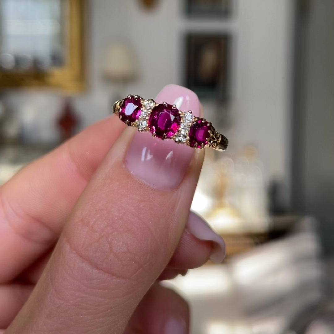 Victorian three-stone ruby and diamond engagement ring, held in fingers and rotated to give perspective. 