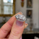 Art Deco three-stone diamond engagement ring, held in fingers and rotated to give perspective.
