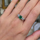Vintage Art Deco three-stone emerald and diamond engagement ring, worn on hand and rotated to give perspective. 