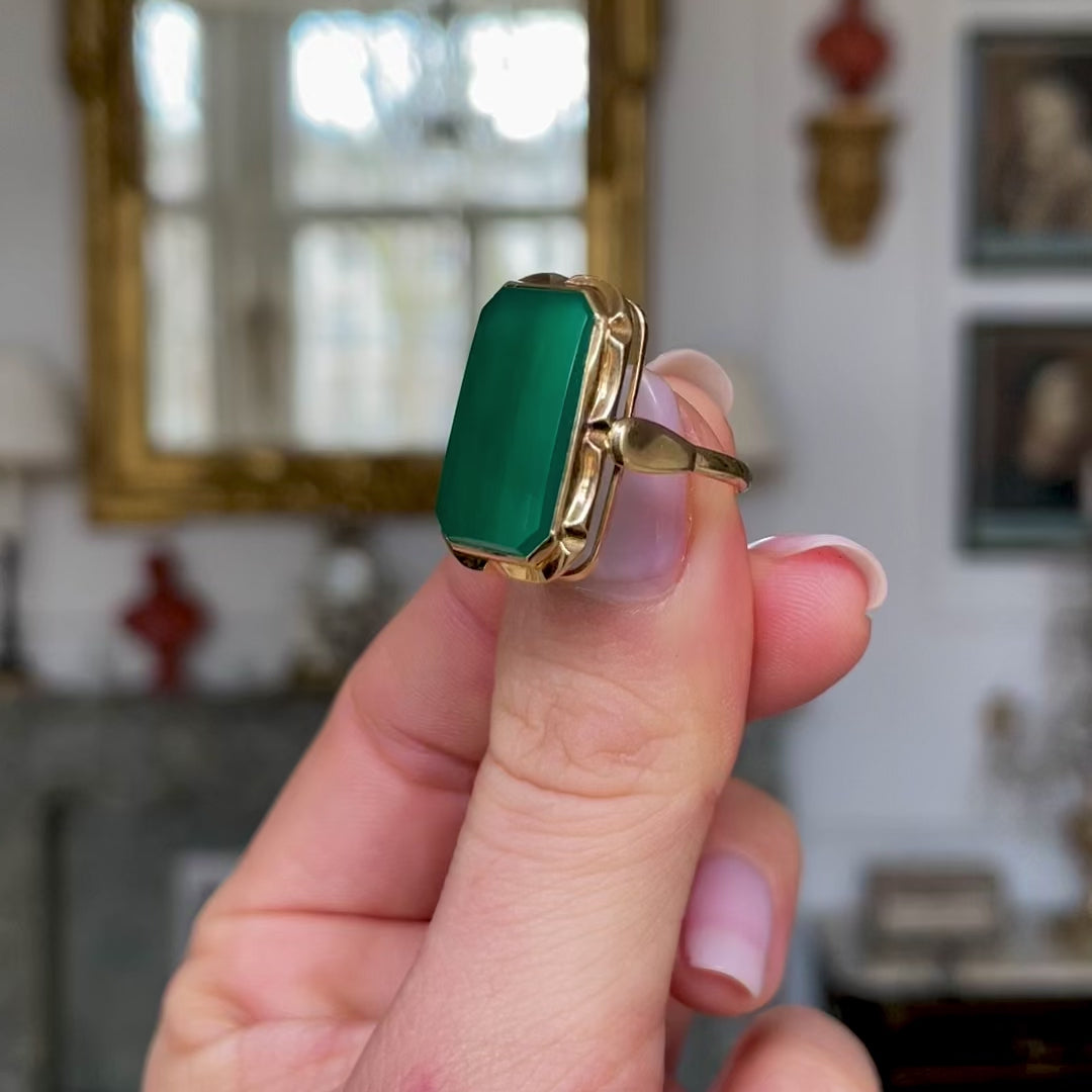 Art Deco chrysoprase and yellow gold ring, held in fingers and moved around camera to give perspective.