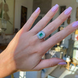 Vintage emerald and diamond cluster ring, worn on hand.