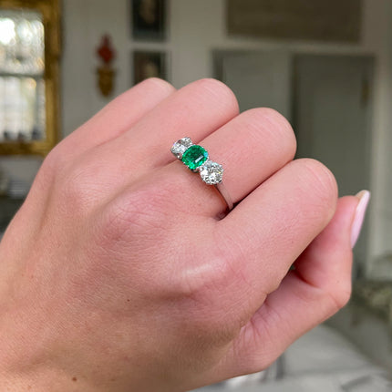 close up of  three stone, platinum, diamond and emerald ring on hand