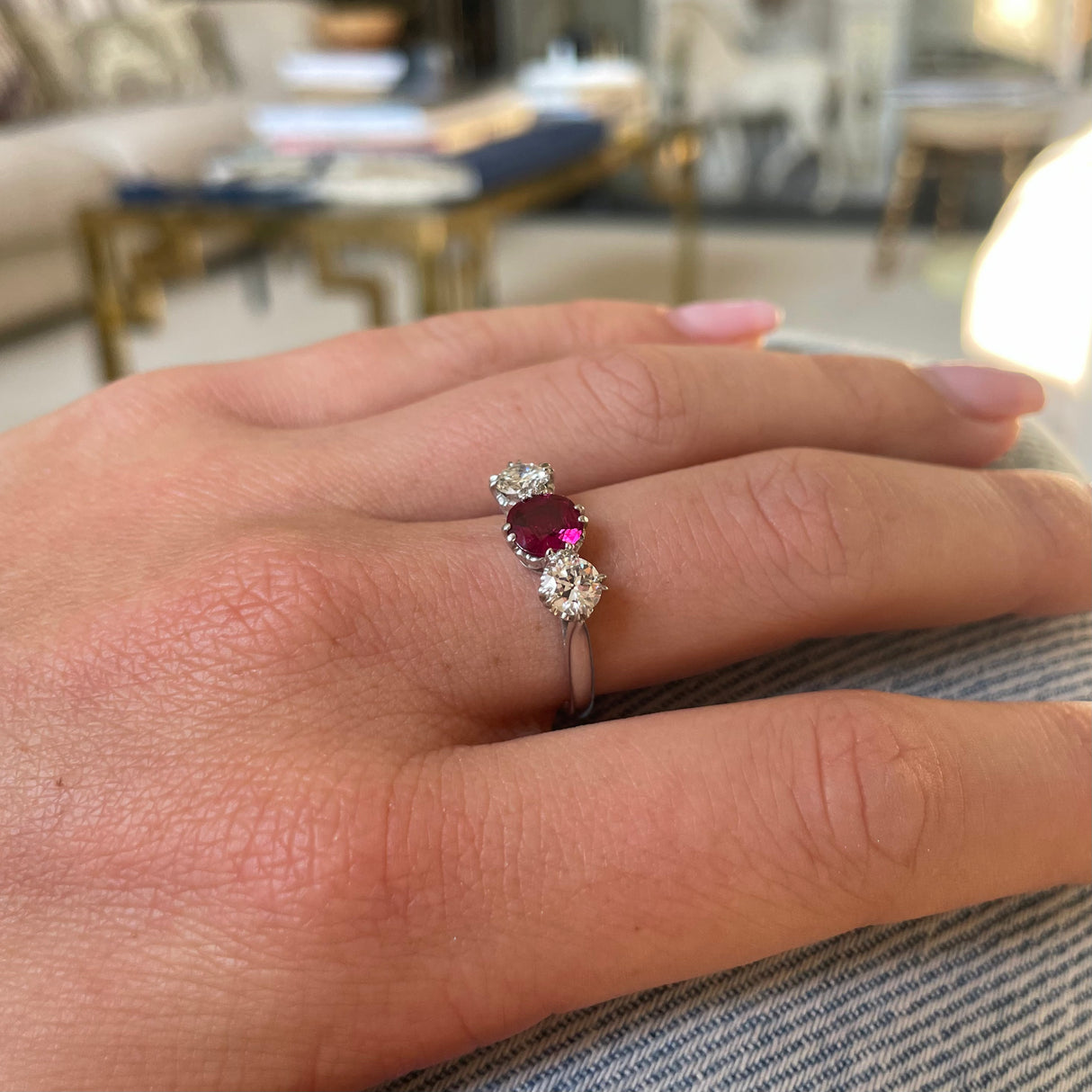 Ruby and diamond three-stone engagement ring, worn on hand.