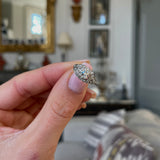 Art Deco diamond engagement ring, held in fingers.