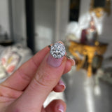 Vintage Art Deco white gold diamond cluster engagement ring,  held in fingers.