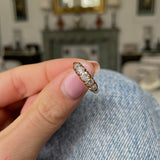 Victorian five stone diamond engagement ring, held in fingers.