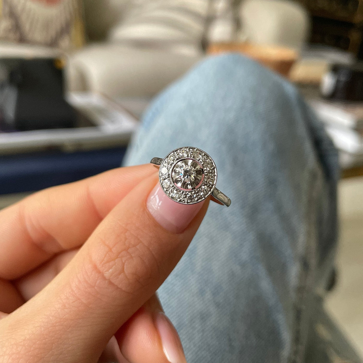 Art Deco diamond cluster engagement ring, held in fingers.