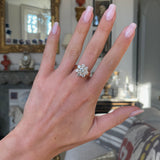 Edwardian diamond cluster engagement ring worn on hand. 
