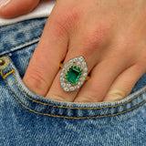 Emerald and diamond navette ring, worn on hand.