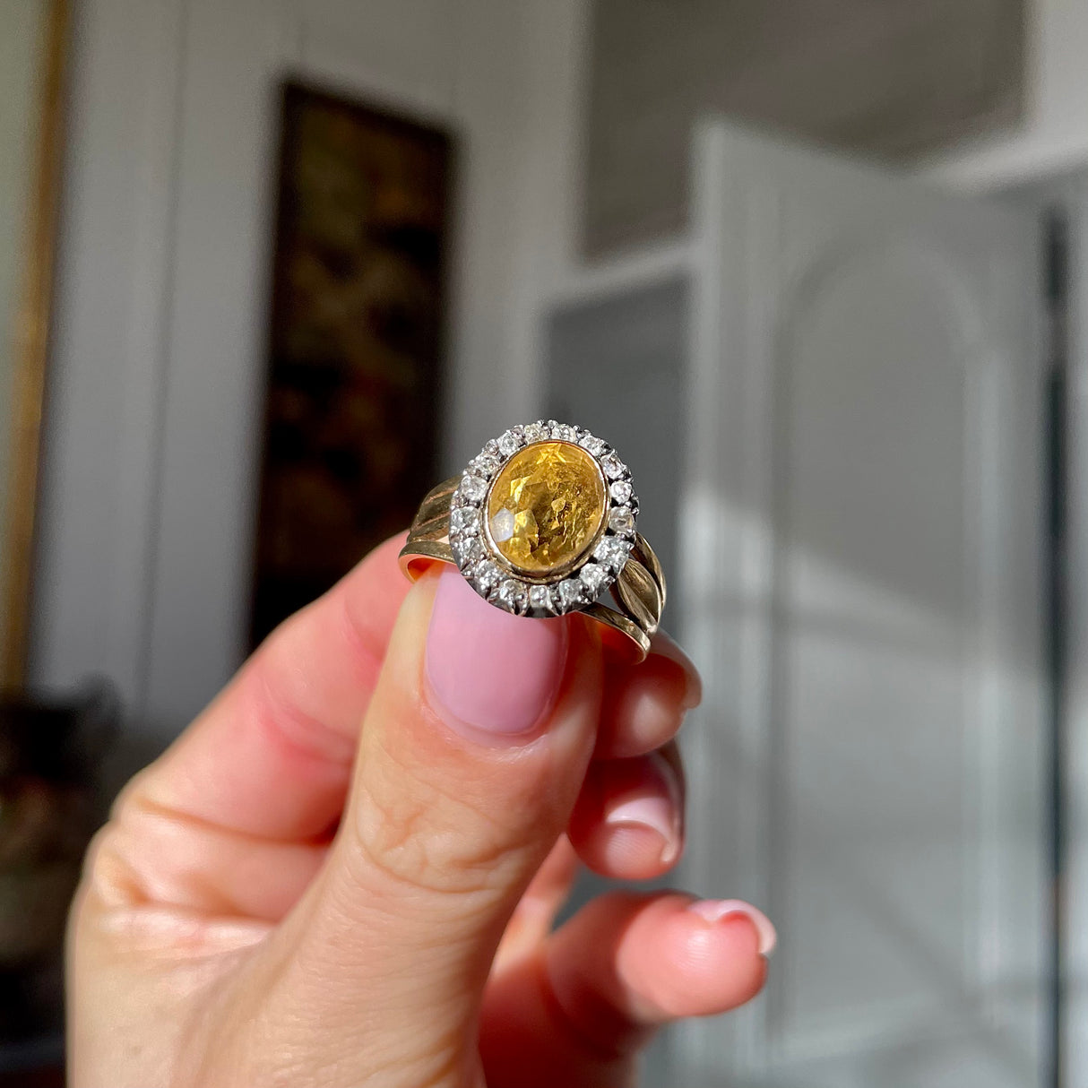 Antique Georgian citrine and diamond cluster ring, held in fingers.